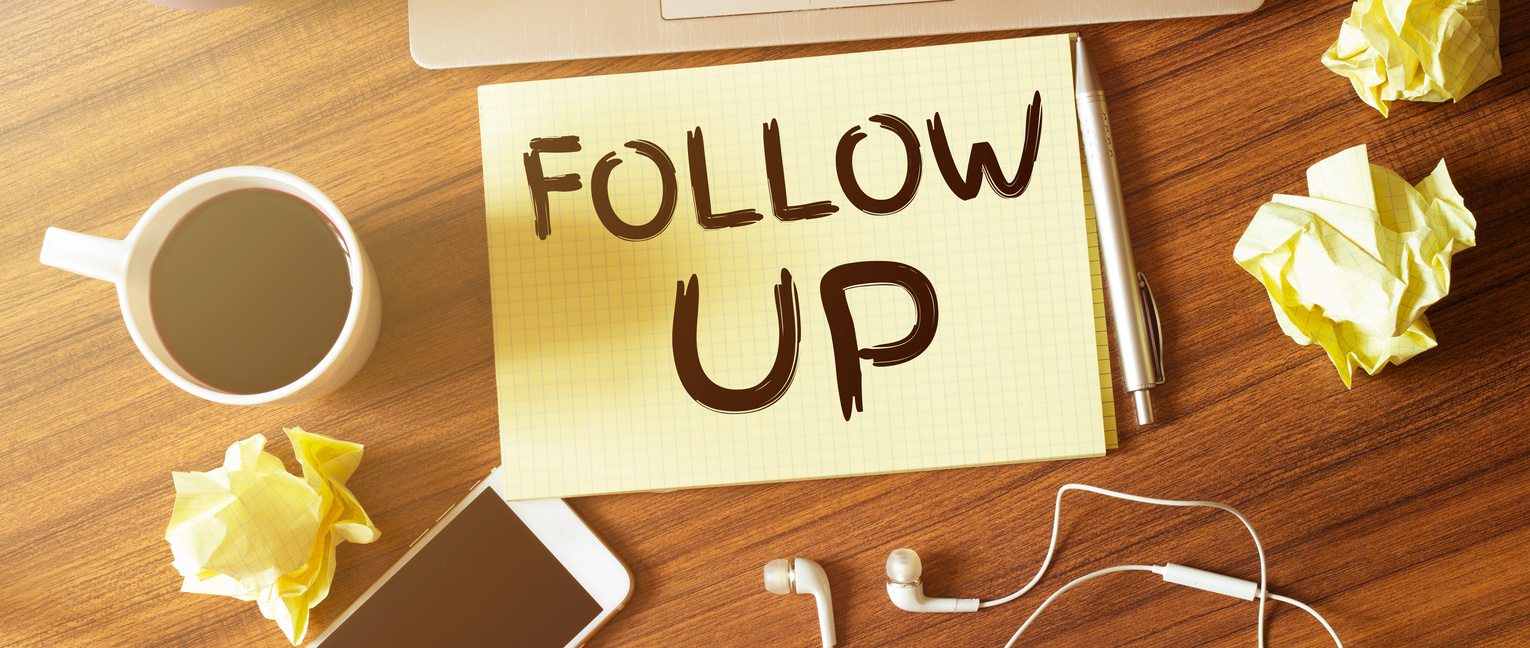 Table with cup of coffee, phone, headphones and paper. FOLLOW UP text